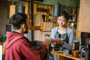 transaction between the female barista and the male customer at the cashier desk