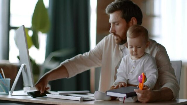 Man talking on phone and working on laptop, babysitting with daughter, cute girl sitting on desk with daddy, free space