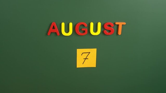 Hand sticking a sticker 7 August calendar day on school board. 7 date of august. Seventh day of august. 7th date number. 7 day calendar. Seven date. Independence day of Ivory Coast, Boyaca Battle