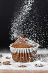 Fresh muffins sprinkled with powdered sugar on a wooden board