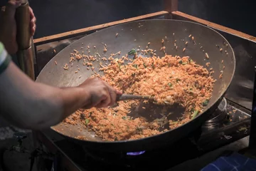 Foto op Plexiglas A man cooking fried rice on steel skillet pan for selling on the street food. Indonesian call the dish Nasi Goreng. Indonesian Street food culinary © Haryanto