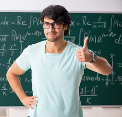 Young male student mathematician in front of chalkboard