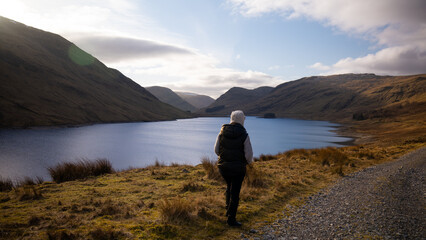 Fototapeta na wymiar lake and mountain view. Woman hiking by the lake