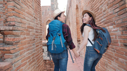 Fototapeta na wymiar Rear View of Two Asian women holding hands walking in the old town. Phra Nakhon Si Ayutthaya, Thailand. Traveling on holidays