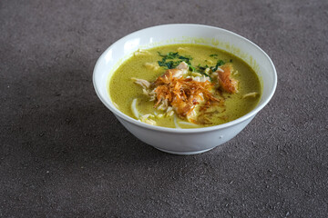chicken yellow soup or soto ayam in white ceramic bowl
