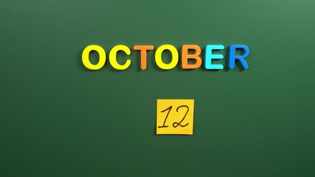 Hand sticking a sticker 12 October calendar day on school board. 12 date of October. Twelfth day of October. 12th date number. 12 day calendar. Twelve date. World Arthritis, Spanish Independence