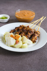 sate ayam, chicken satay with peanut sauce and rice cake

