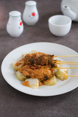 sate ayam, chicken satay with peanut sauce and rice cake
