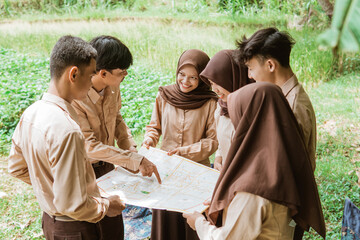 boy scout with finger pointing at map while chatting with group mates