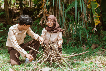 Naklejka premium Girl Scouts and Boy Scouts chat while preparing dry twigs for firewood in nature