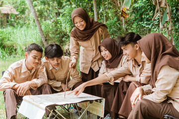 team leader shows the location to the youth scout group with a map during the briefing