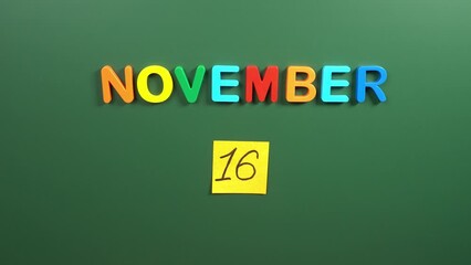 Hand sticking a sticker 16 November calendar day on school board. 16 date of November. Sixteenth day of November. 16th date number. 16 day calendar. Sixteen date. International for Tolerance