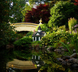 Fototapeta na wymiar Beautiful flower garden with pond and small green house