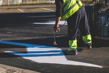 Process of making new road surface markings with a line striping machine, workers improve city infrastructure, demarcation marking of pedestrian crossing with a hot melted paint on asphalt pavement - Powered by Adobe