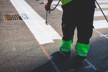 Process of making new road surface markings with a line striping machine, workers improve city infrastructure, demarcation marking of pedestrian crossing with a hot melted paint on asphalt pavement
