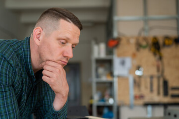 Naklejka premium Portrait of a pensive caucasian man in a workshop. 