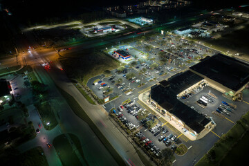 Aerial night view of many cars parked on parking lot with lines and markings for parking places and directions. Place for vehicles in front of a grocery mall store © bilanol