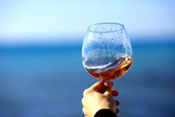 a glass of port wine on the background of the sea, a hand with wine