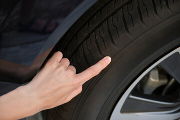 Female driver hands inspecting wheel tire of her new car. Vehicle safety concept © bilanol