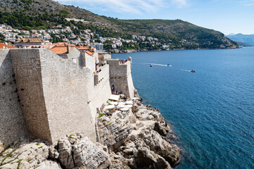 View some of the Mediterranean sea with boats and the exterior walls of the old town of Dubrovnik, Croatia, a remarkably well-preserved UNESCO site.