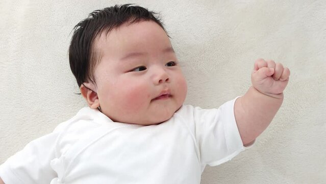 自分の手を見つめる赤ちゃん。ハンドリガードのイメージ（0歳3か月、日本人、男の子）