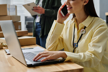 Close-up of young female volunteer in yellow shirt consulting people online and on the phone while...