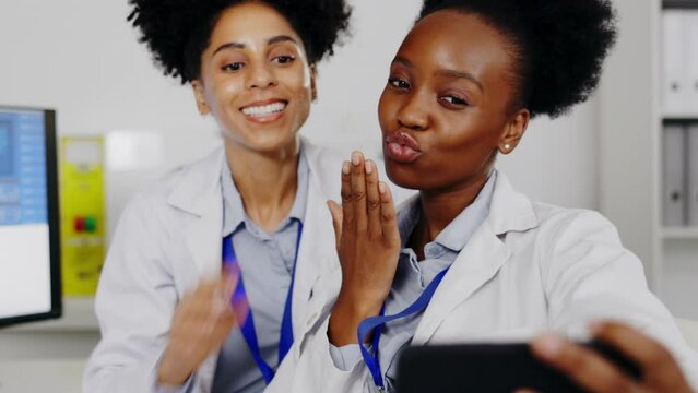 Women, scientist and peace sign selfie in lab for happy memory, social media or profile picture. Science smile, teamwork and medical doctors or friends taking photo with v hand emoji and air kissing.