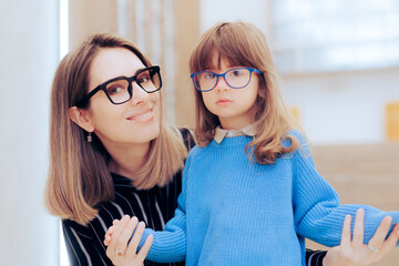 Mother and Daughter Wearing Eyeglasses in an Ophthalmology Clinic. Mom and child choosing stylish...
