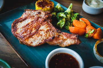Well done grilled pork chop steak in  plate and vegetable salad