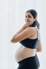 Fototapeta premium Pregnant beautiful woman is wearing sportive black clothes isolated on background, healthy life concept
