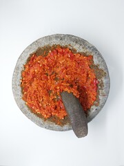Indonesian Sambal Geprek chili sauce with tomato and garlic chili serve on pestle mortar stone called cobek