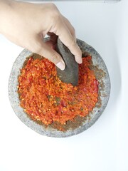 Indonesian Sambal Geprek chili sauce with tomato and garlic chili serve on pestle mortar stone called cobek
