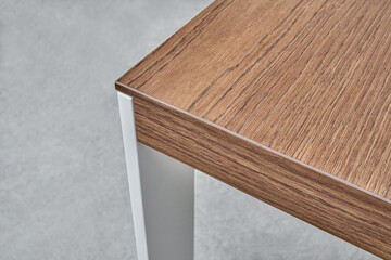 Minimalism style dining table with thin wooden table top of toned oak veneer on white metal legs closeup