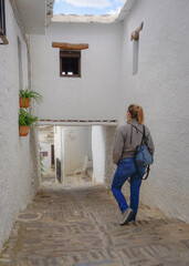 Plakat Young white blonde woman dressed in jeans walking through a village in the Alpujarra of Granada
