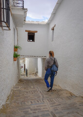 Obraz na płótnie Canvas Young white blonde woman dressed in jeans walking through a village in the Alpujarra of Granada
