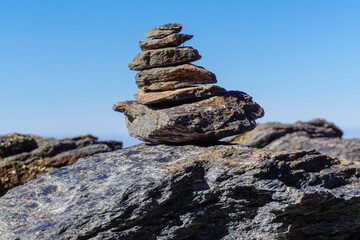 Flat gray stones piled up forming a pyramid and marking the path of a path in the mountains