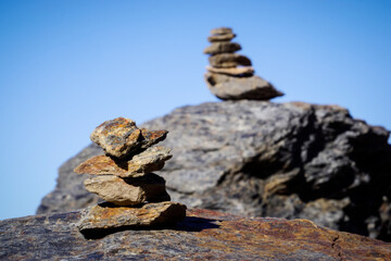 Flat gray stones piled up forming a pyramid and marking the path of a path in the mountains