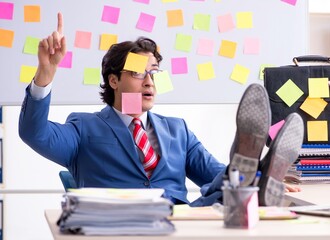 Young male handsome employee in conflicting priorities concept