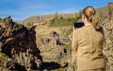 Naklejka premium Beautiful young and blonde woman taking photos in a canyon of the Alpujarras region of Granada