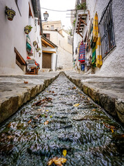 Fototapeta premium street of a town in the Alpujarra of Granada with water running through a canal in the center of the road