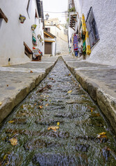 street of a town in the Alpujarra of Granada with water running through a canal in the center of the road