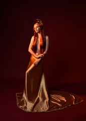 Full length fantasy portrait of beautiful woman model with red hair, goddess silk robes & gold...