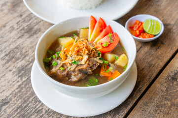 Delicious Oxtail Soup or Soup Buntut Served with Chili Sauce or Sambal and Steam Rice