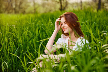 Naklejka na ściany i meble adorable woman sitting in nature resting in tall grass
