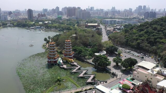 Scenery of Lianchihtan Lotus Lake, a popular tourist attraction in Zuoying, Kaohsiung, Taiwan, with Dragon & Tiger Pagodas connected by the zigzag Nine Turn Bridge & high rise buildings in background