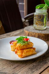 Delicious Asian Snack Spring Rolls or Lumpia Served with Chili Sauce on White Plate