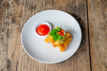 Delicious Asian Snack Spring Rolls or Lumpia Served with Chili Sauce on White Plate