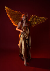 Full length portrait of beautiful woman model with long red hair, gold silk robes, crown & fantasy...