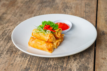Delicious Asian Snack Spring Rolls or Lumpia Served with Chili Sauce on White Plate