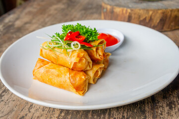 Delicious Asian Snack Spring Rolls or Lumpia Served with Chili Sauce on White Plate